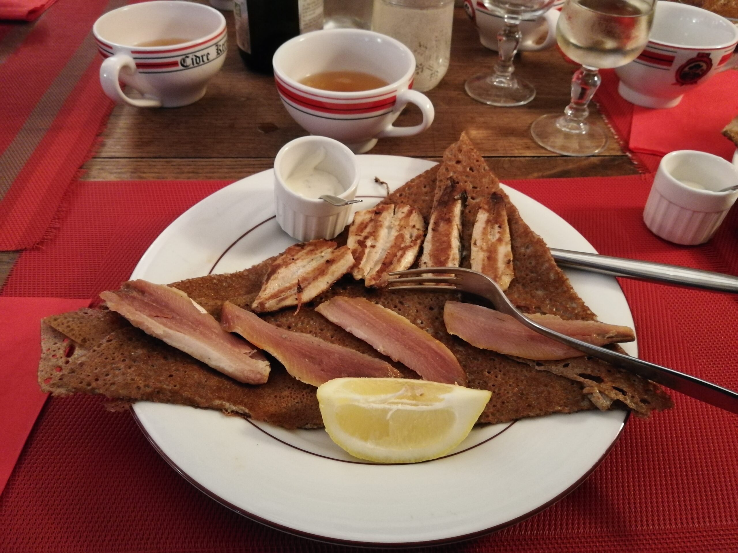 Galette bretonne garnie au poisson, servie avec citron et sauce à la Crêperie de Keroman